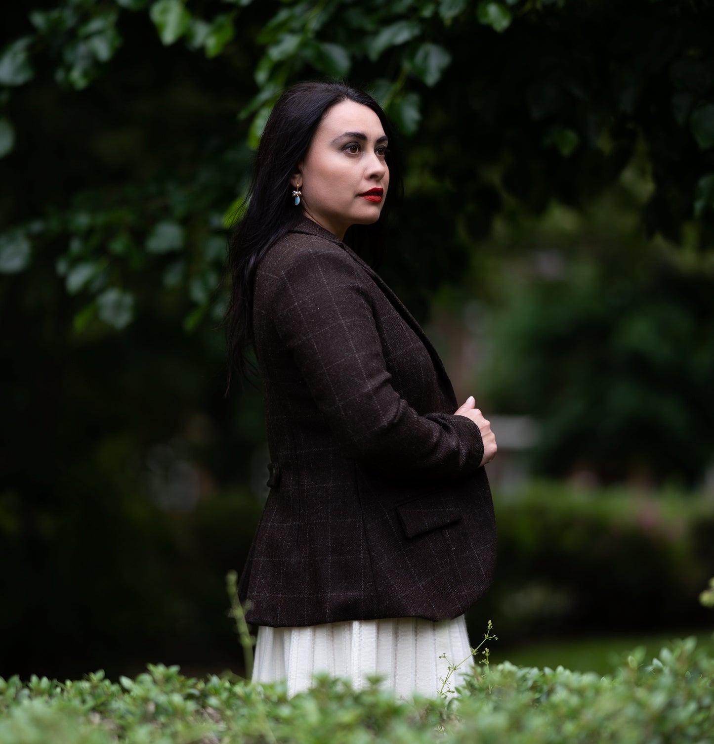 Side view highlighting the drape and the shoulder line of the brown tweed wool jacket.