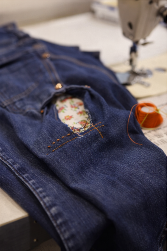 Finished repaired denim jeans showing patch and reinforcement stitching after a clothing repair class in London.