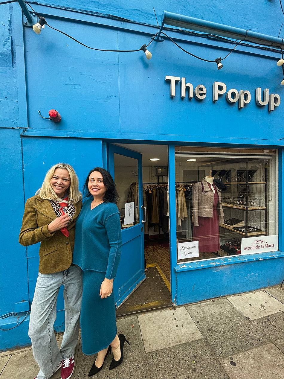 Maria Ruseva wearing a blue cashmere suit beside Lucia in a green tweed jacket and silk scarf outside The Pop Up on Lillie Road, Earl’s Court, London — part of the Moda de la Maria sustainable fashion showcase.