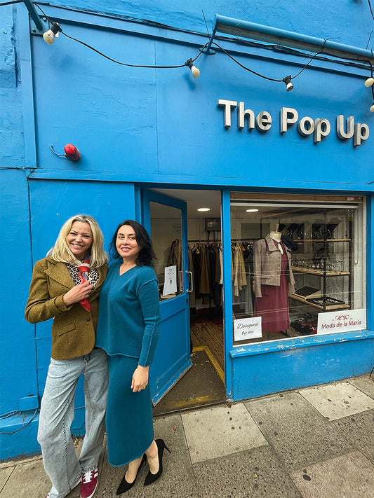 Maria Ruseva wearing a blue cashmere suit beside Lucia in a green tweed jacket and silk scarf outside The Pop Up on Lillie Road, Earl’s Court, London — part of the Moda de la Maria sustainable fashion showcase.