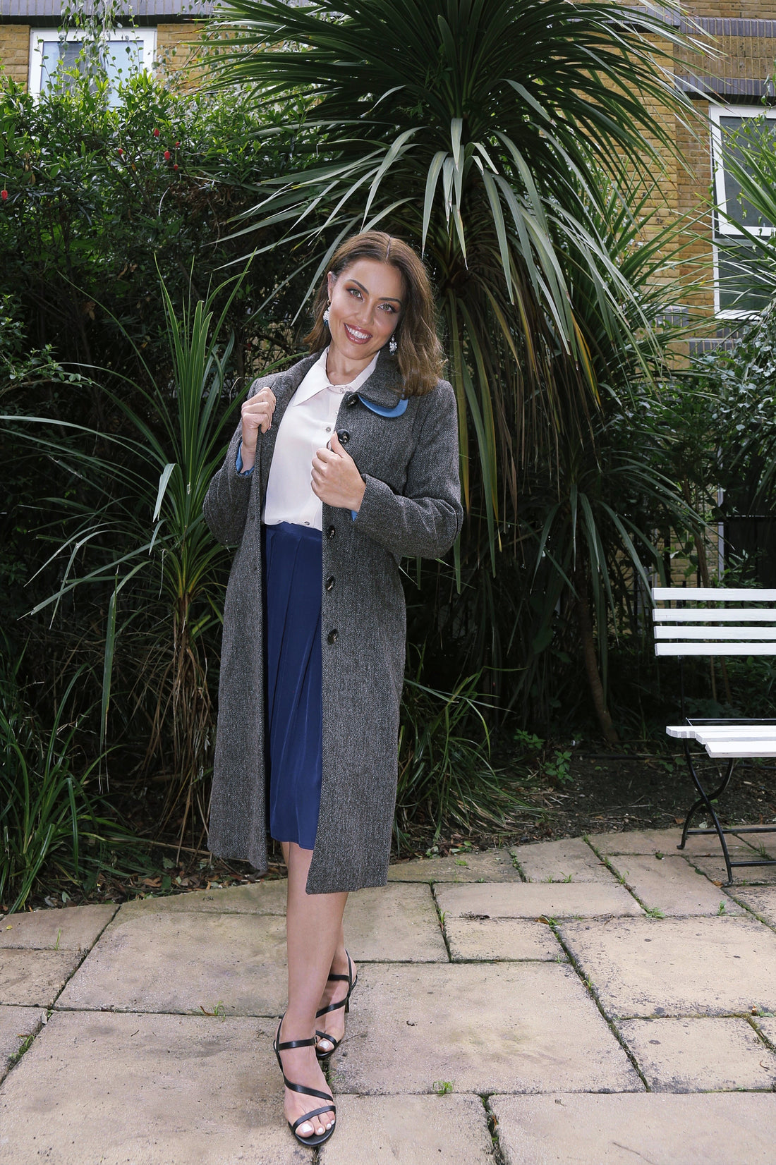 Woman wearing a handcrafted organic wool tweed coat and silk skirt representing timeless luxury fashion and natural fabric craftsmanship.