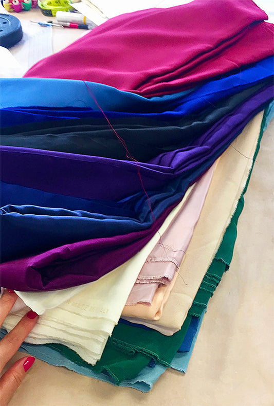 Luxury natural fabrics in rich jewel tones including silk cotton and wool at Moda de la Maria London atelier