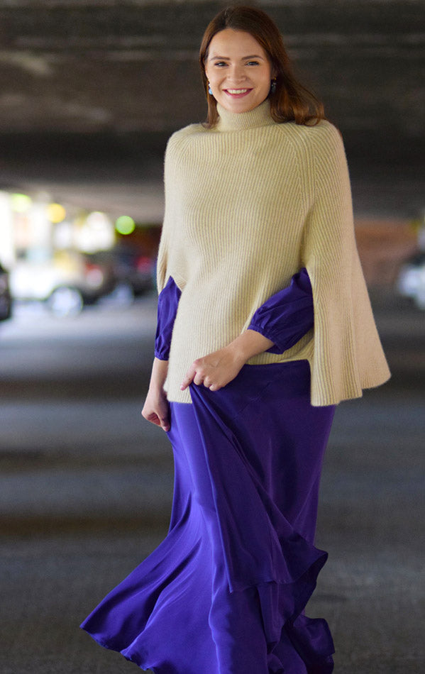 Organic cashmere cape layered over a silk dress, blending warmth with sophistication.