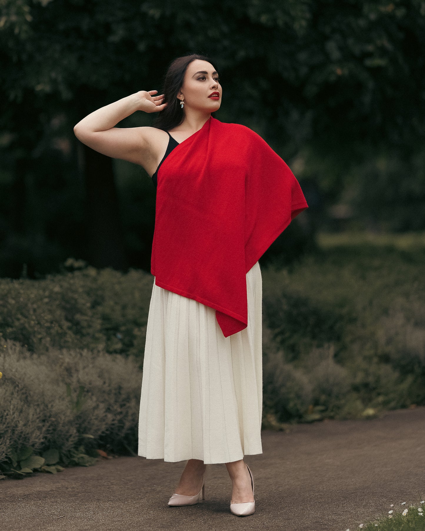 Model wearing cashmere poncho shawl draped open as a cape, fine-knit cashmere with metallic side buttons.