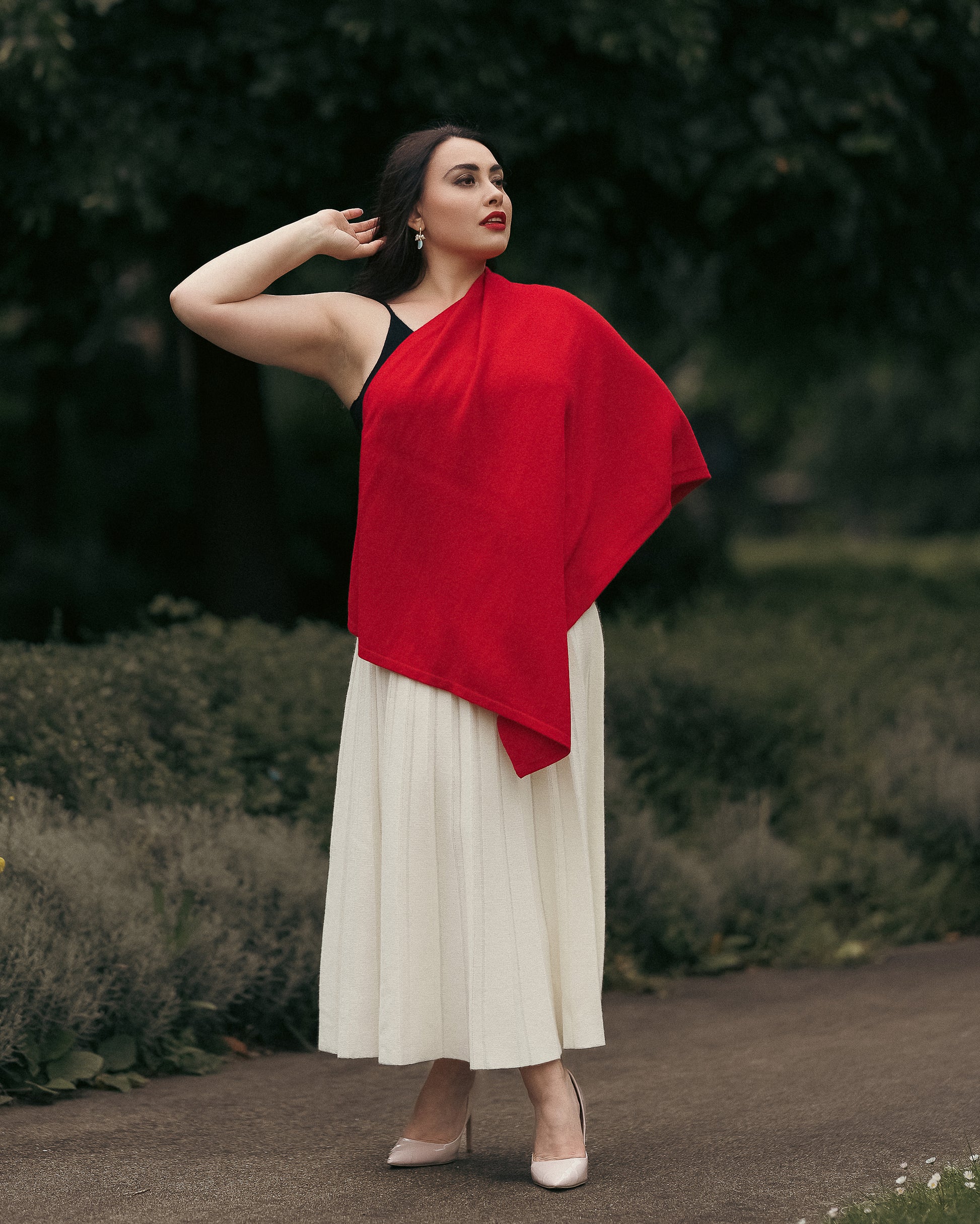 Model wearing cashmere poncho shawl draped open as a cape, fine-knit cashmere with metallic side buttons.