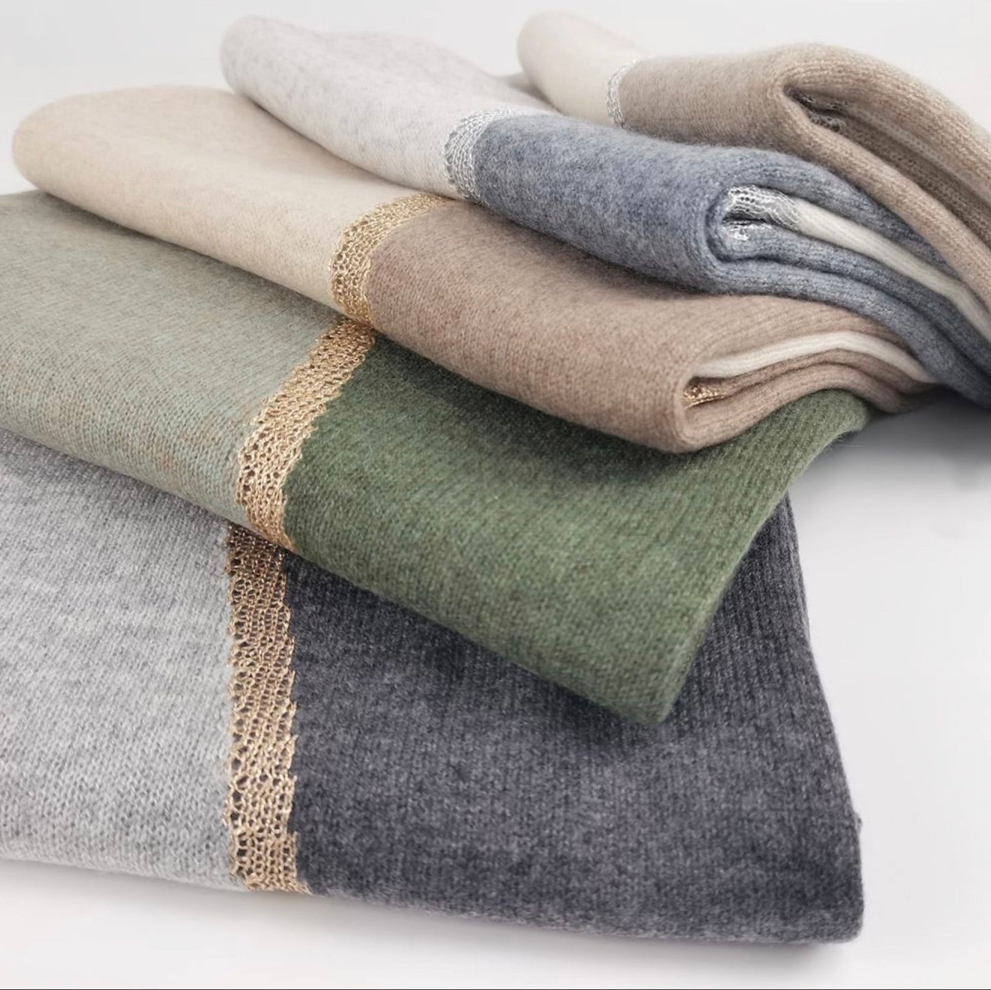 Elegant woman wearing Moda de la Maria 100% pure cashmere colour-block pashmina scarf in sage green, taupe and cream against a pure white background.