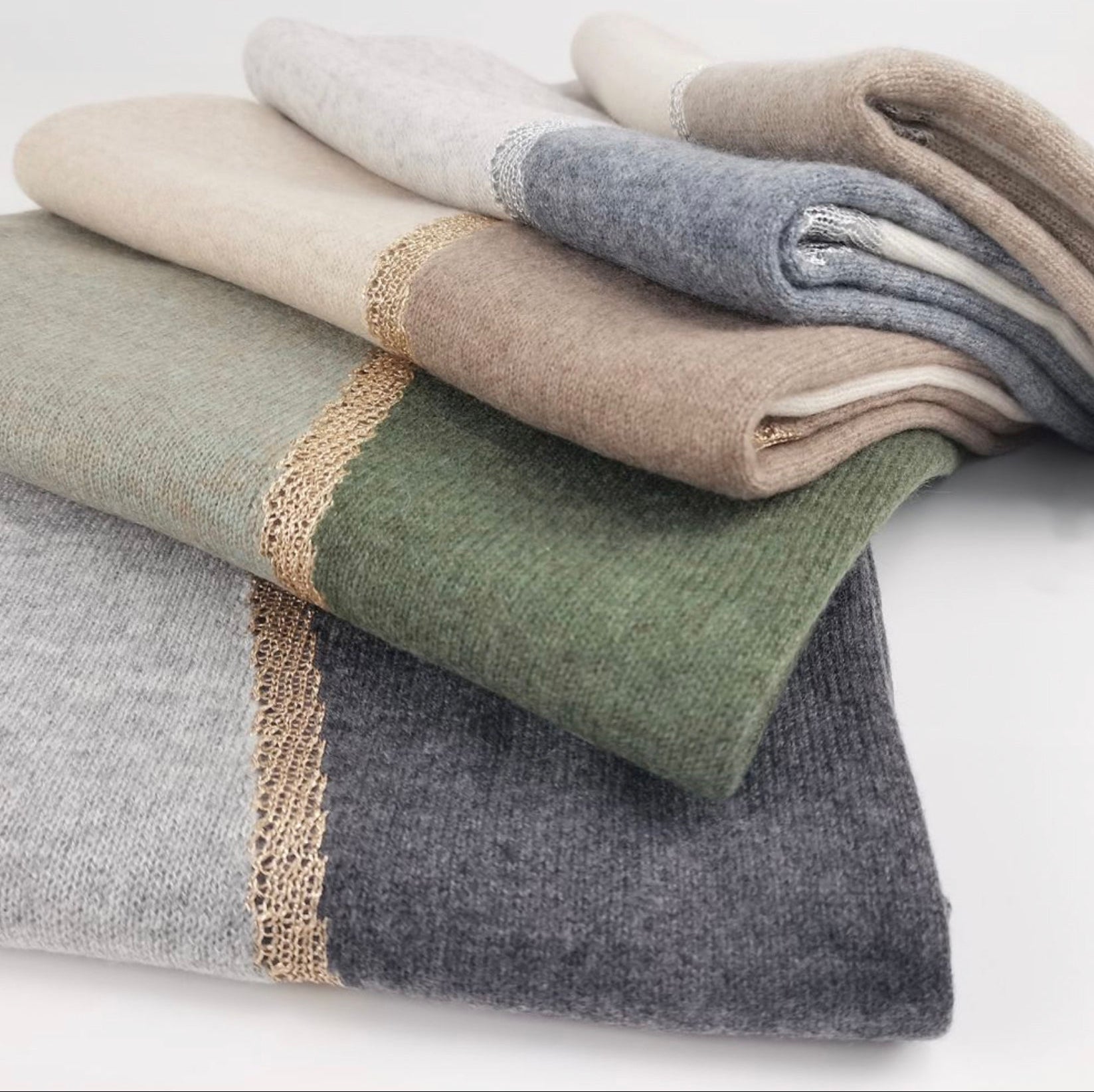 Elegant woman wearing Moda de la Maria 100% pure cashmere colour-block pashmina scarf in sage green, taupe and cream against a pure white background.