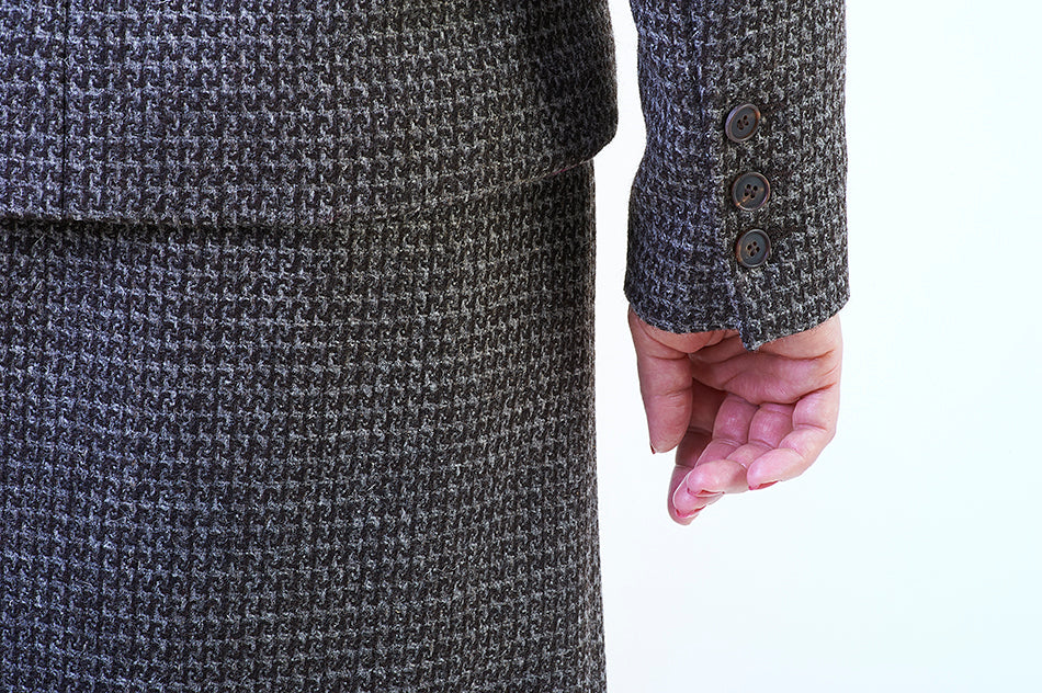 Close-up of vented back closure and sleeve horn button detailing on luxury tweed jacket, slow fashion made in England.