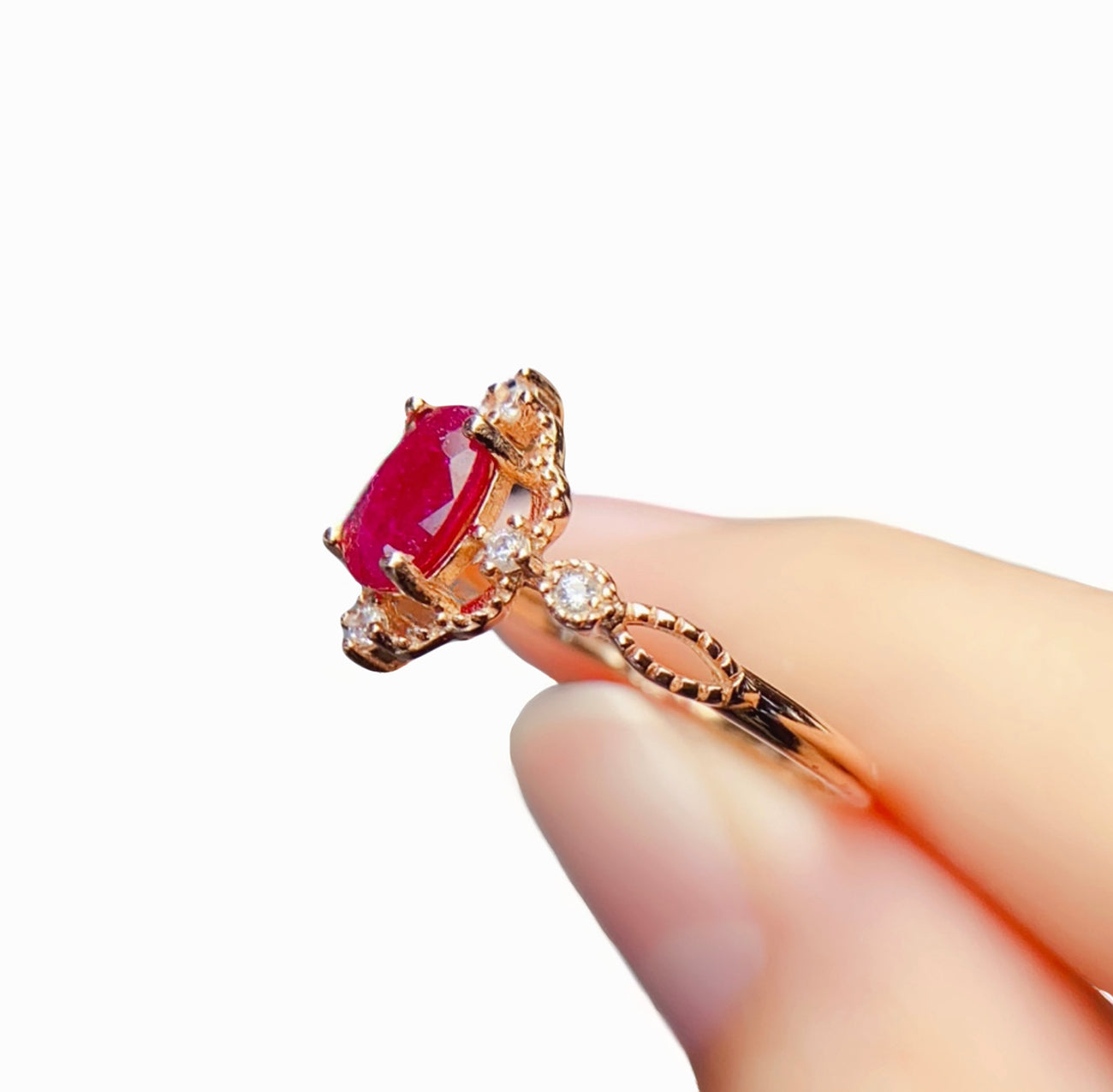Side view of rose gold plated sterling silver ruby ring with halo and cubic zirconia accents.
