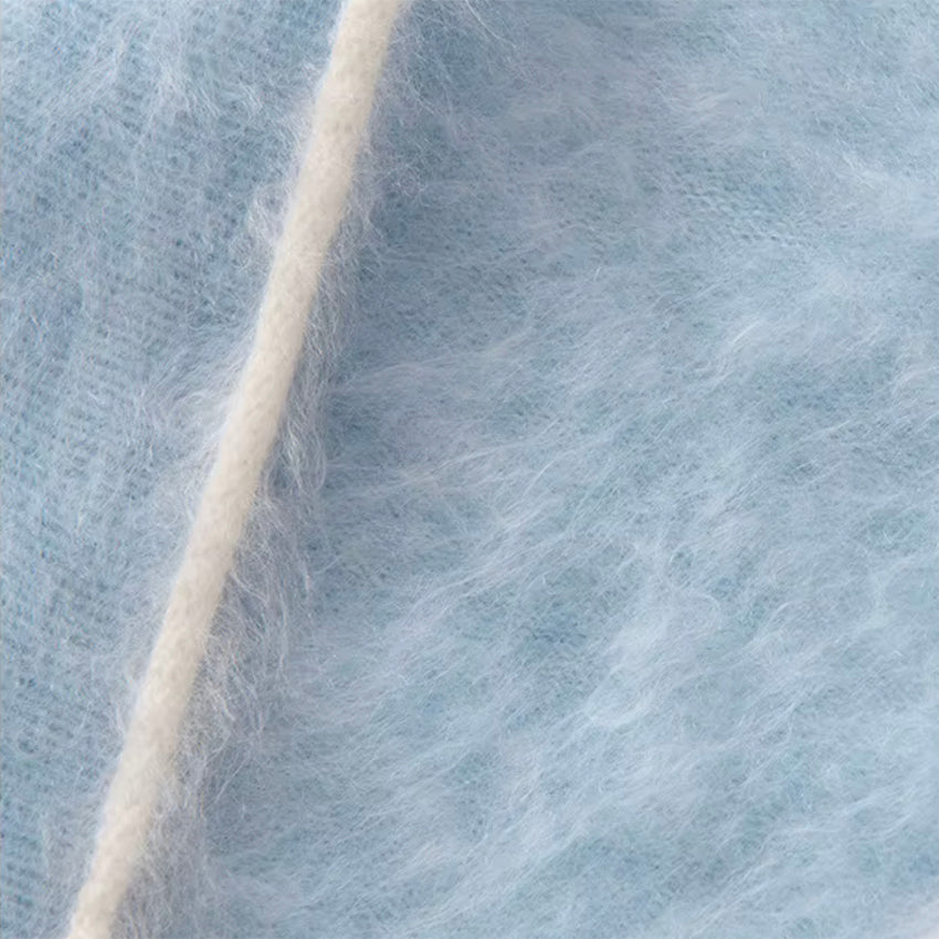 Close-up of blue cashmere triangle scarf showing soft fluffy fibres and delicate cream contrast trim