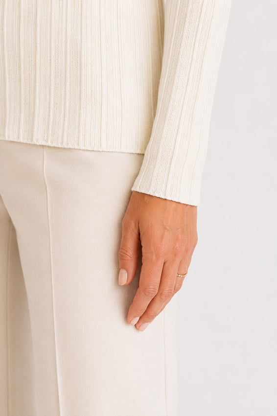 Close-up of the luxurious ribbed knit texture in a cream women's top.