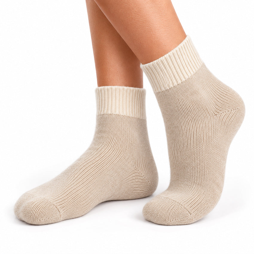 Women's light cream pure cashmere ankle socks by Moda de la Maria shown worn on the feet against a white background.