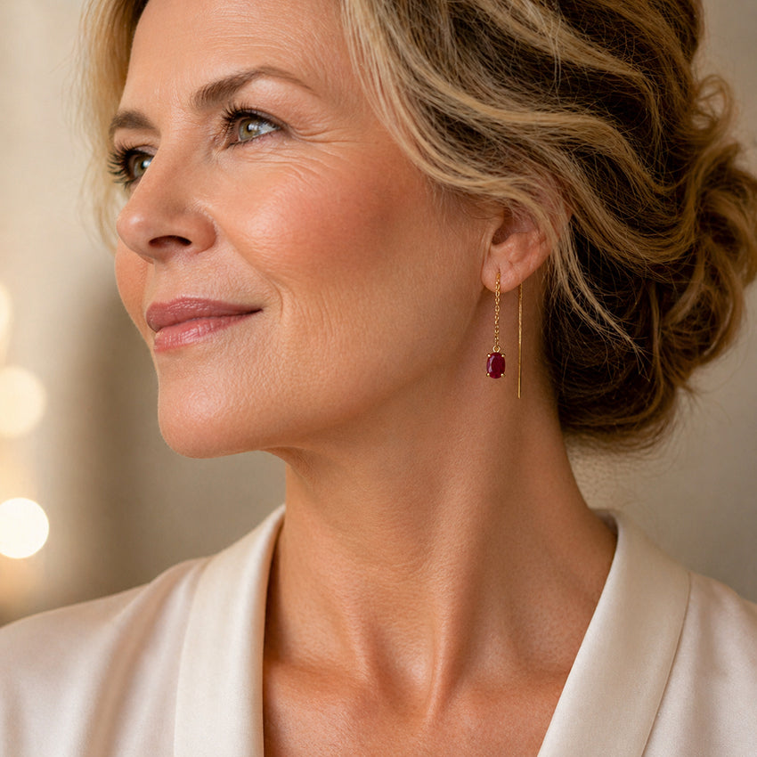 Elegant mature woman wearing Moda de la Maria natural ruby threader earrings in 18K gold plated sterling silver, featuring deep red oval ruby gemstones on fine chain earrings styled for luxury, timeless jewellery for women over 40
