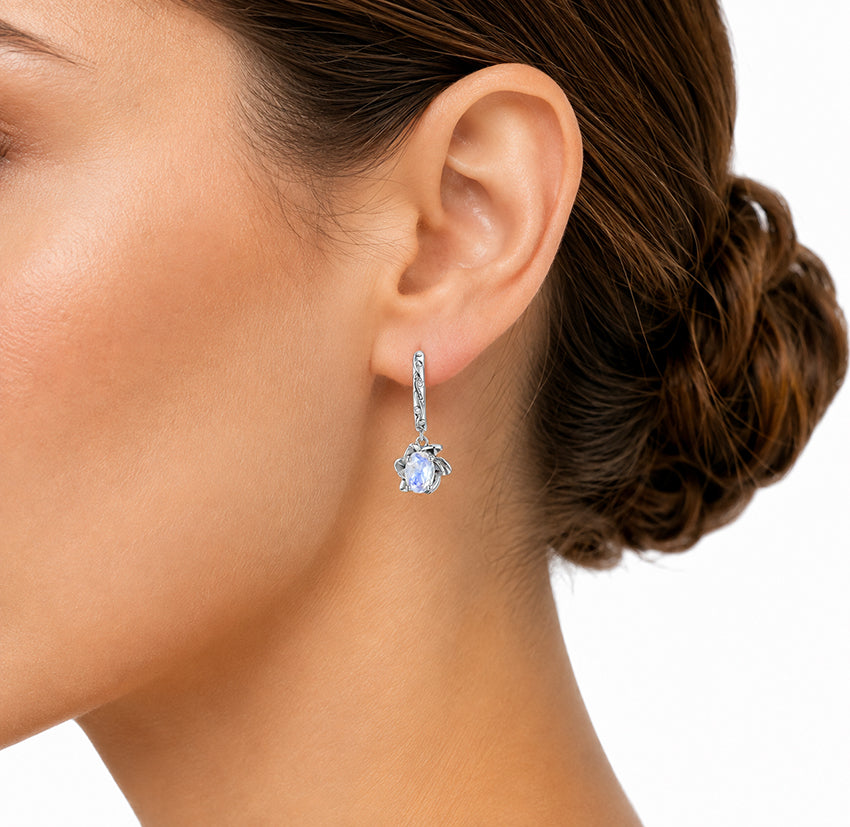 Close-up of moonstone drop earring worn on the ear showing its size and floral design