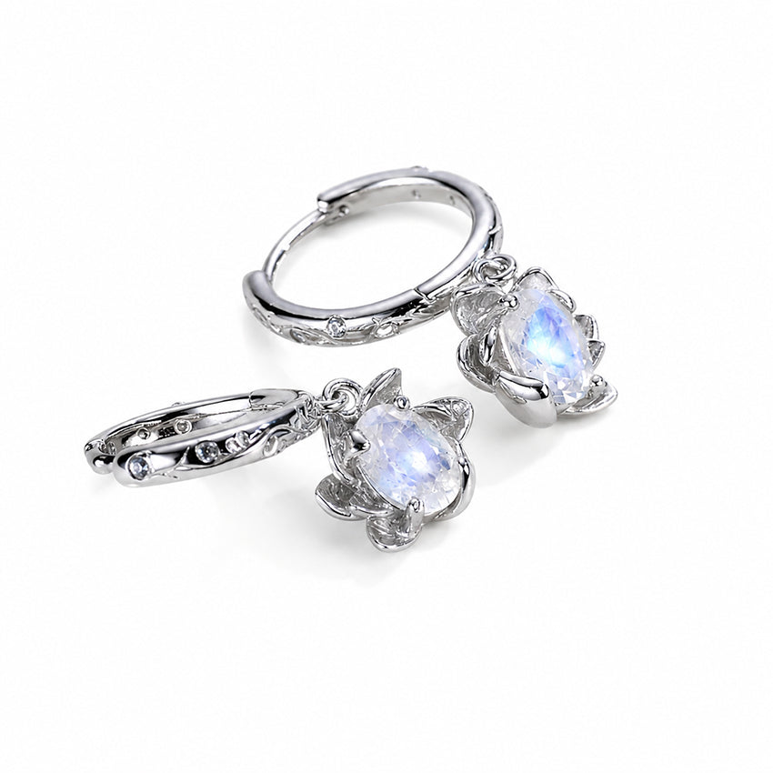 Close-up of oval moonstone earrings with floral silver settings and engraved hoop details
