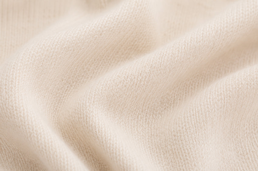 Macro close-up of soft organic cashmere knit texture in natural ivory