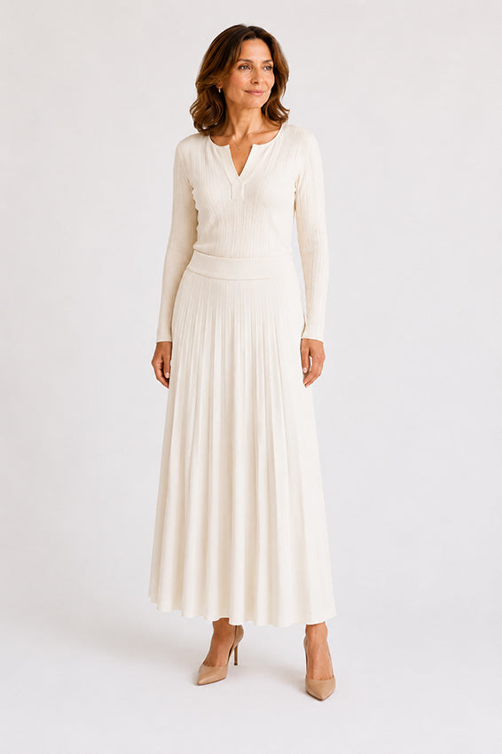 Organic cashmere ivory knitted skirt styled on a woman over 40, elegant front three-quarter view showing the flattering silhouette and soft drape.