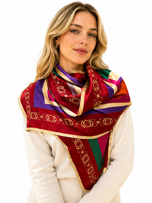 Blonde model wearing a luxury silk scarf with burgundy, purple, emerald and gold geometric detailing, styled elegantly on a white background for sustainable luxury fashion by Moda de la Maria.