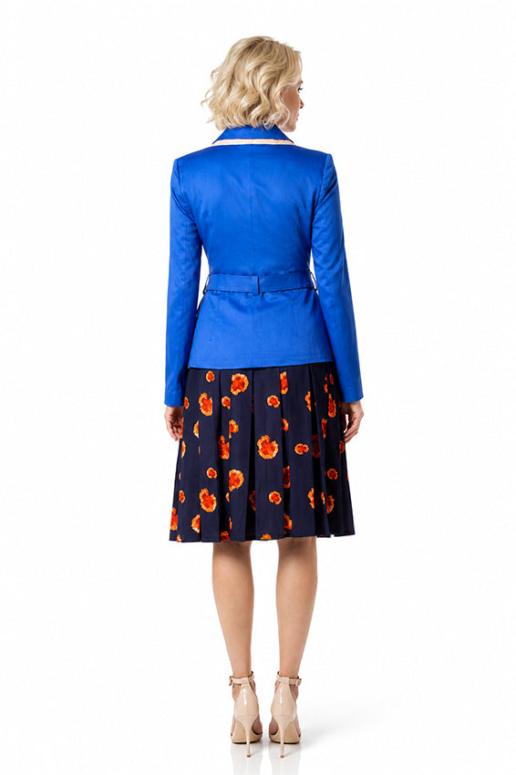 Back view of a woman wearing a handcrafted royal blue tailored jacket with a fitted silhouette and belt detail, styled with a navy floral skirt on a pure white background.
