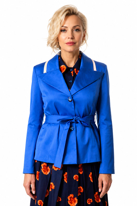 Woman wearing a handcrafted royal blue tailored jacket with a belted waist over a navy floral blouse and skirt, photographed on a pure white background. Luxury slow fashion womenswear by Moda de la Maria.
