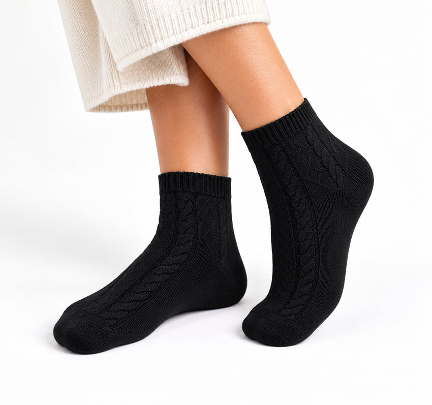 Women’s black 100% cashmere cable-knit ankle socks worn on model against a white background