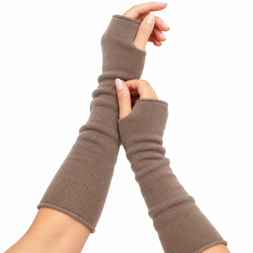 Women’s taupe pure cashmere long fingerless gloves worn on the hands, showing their soft knit texture, thumb openings and extended length.